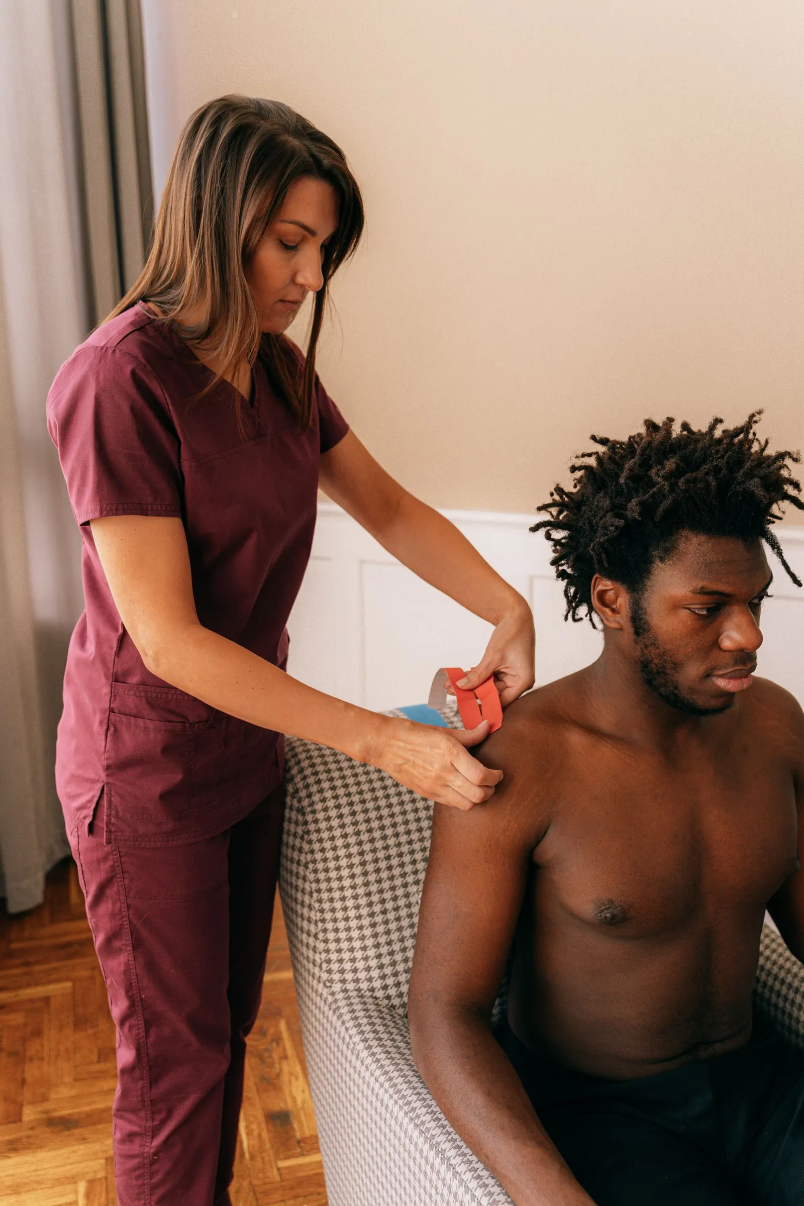 Therapist applying kinesiology tape to an athlete's shoulder